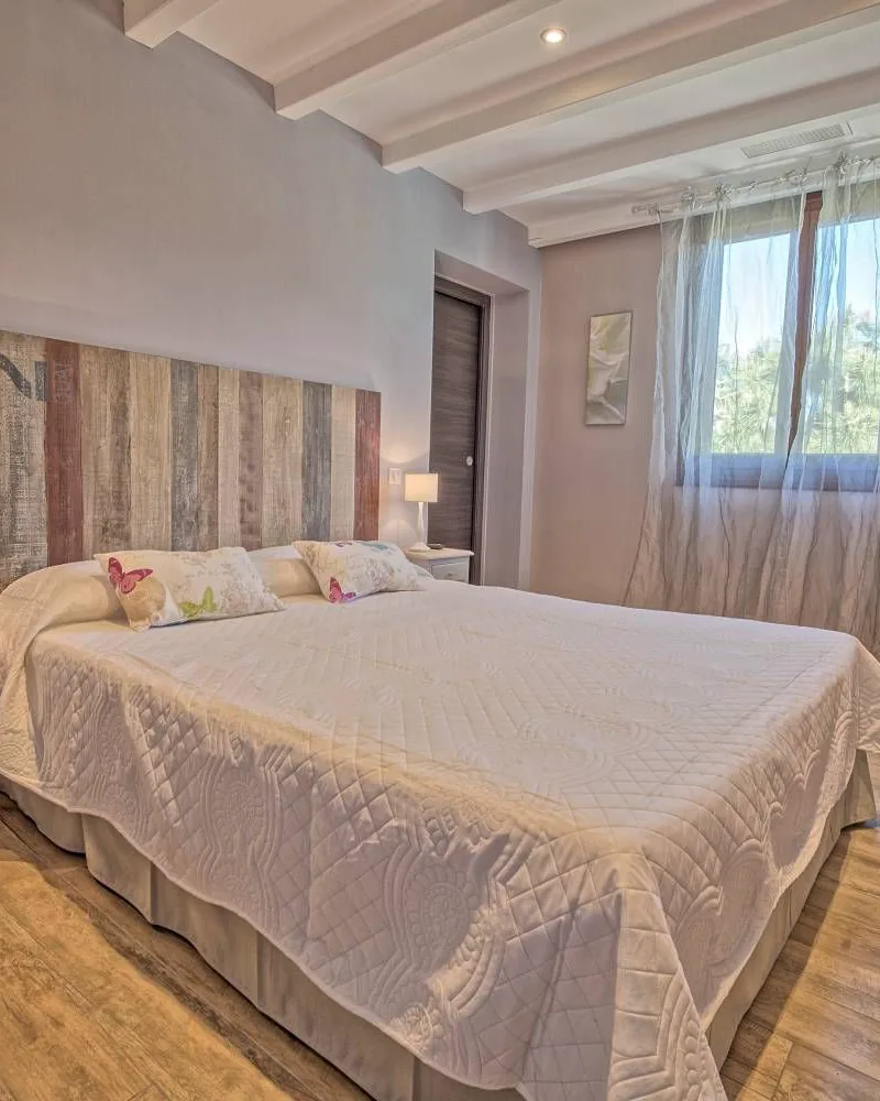 Chambre double classique : grand lit, tête de lit en bois, fenêtre sur la verdure