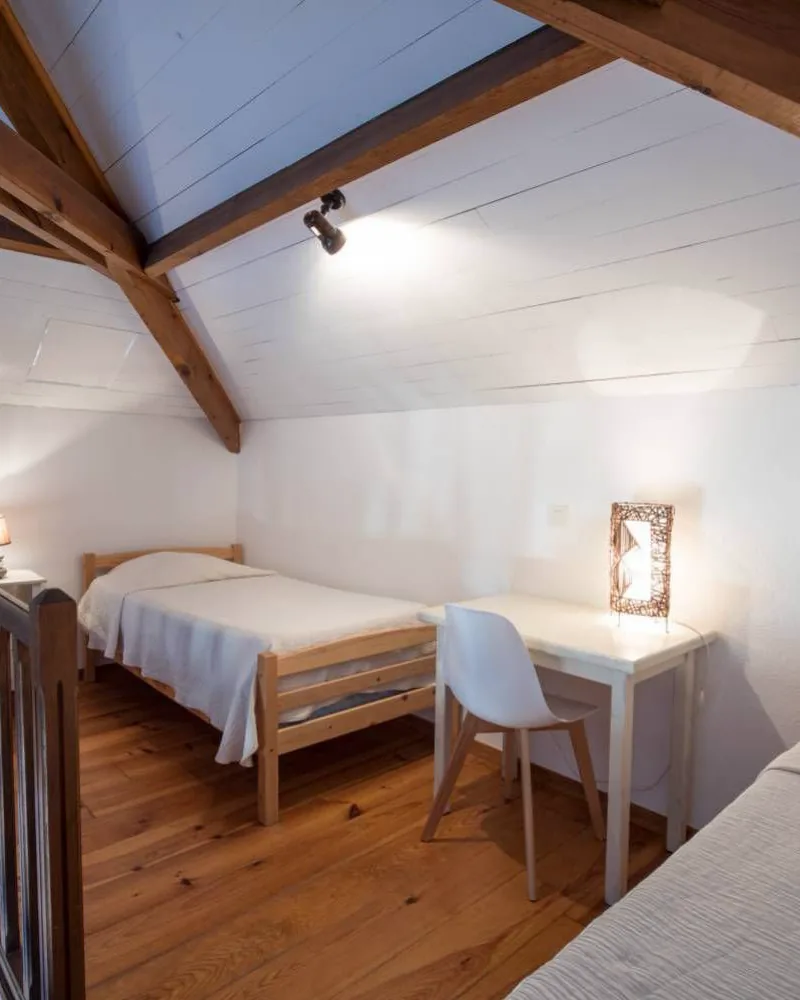 Mezzanine du duplex sous la charpente, avec deux lits simples et un bureau